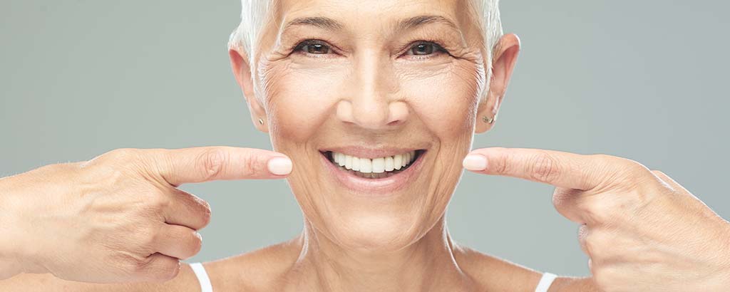 a woman points to her dental crowns with cerec