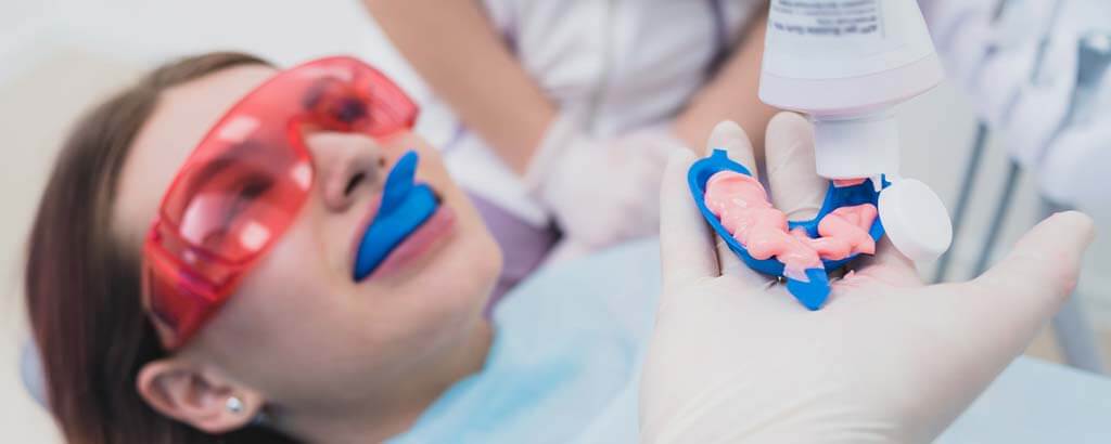 a dentist pours fluoride into a try for a woman's fluoride treatments