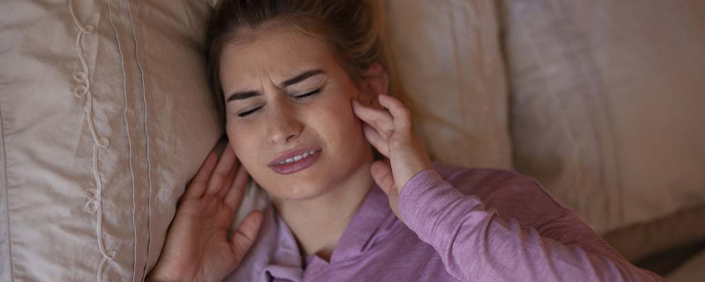 a woman rubs her jaw and considers getting neuromuscular dentistry for tmd relief