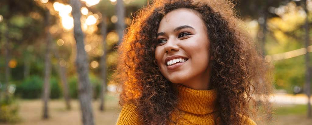 a woman in a park considers orthodontic treatment