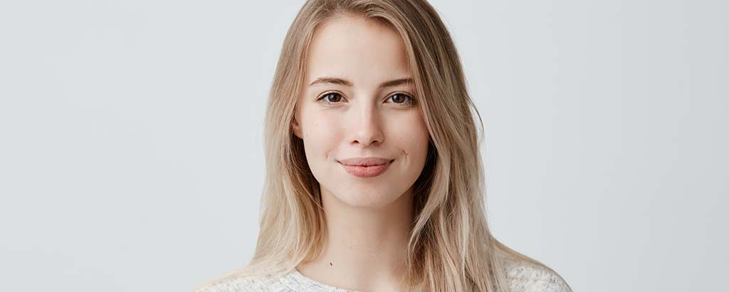 a woman smiles hesitantly after getting tooth perforation repair