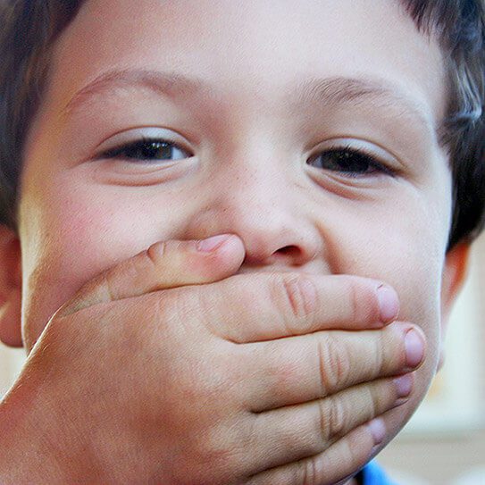 a boy covers his mouth as he prepares for dental emergencies