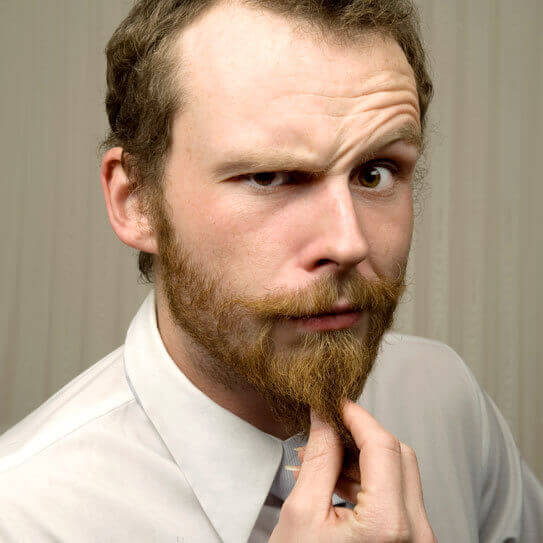 a man strokes his beard as he considers the connection between gum disease and dementia