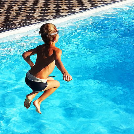 a boy jumps into a pool and thinks about how saliva is the unsung hero of oral health