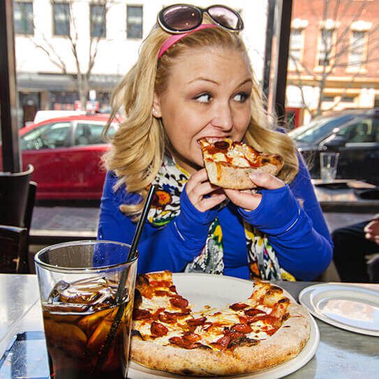 a woman burns her mouth on pizza