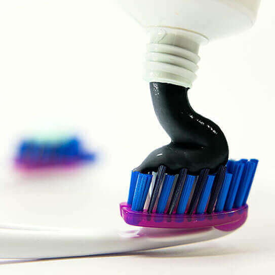 a charcoal toothpaste is squirted onto a toothbrush