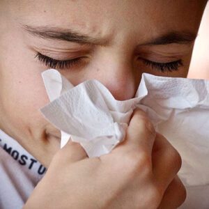 a boy blows his nose and thinks about cold and flu season and oral health